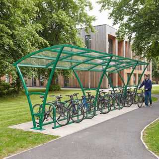 Armstrong 24 cycle bike shelter in Traffic Green on a leafy university campus path with bicycles parked