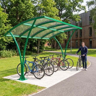 Armstrong CHS 10 cycle curved bike shelter in Traffic Green on a leafy university campus path with bicycles parked