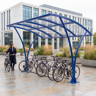 Armstrong CHS 10 cycle curved bike shelter in Ultramarine Blue in a modern university library courtyard with bicycles parked