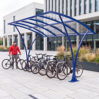 Armstrong CHS 12 cycle curved bike shelter in Ultramarine Blue in a modern university library courtyard with bicycles parked