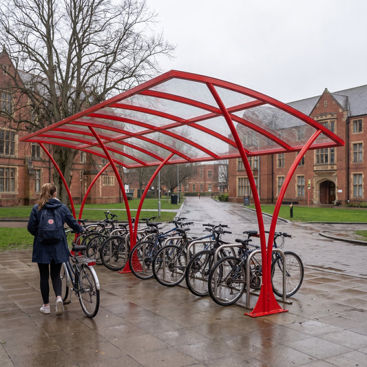 Armstrong CHS 20 cycle curved bike shelter in Traffic Red at a UK university with a student arriving by bike