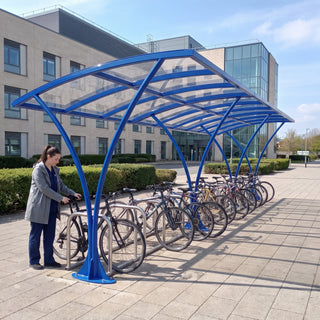 Armstrong CHS 24 cycle curved bike shelter in Ultramarine Blue at a UK hospital with a nurse unlocking her bike